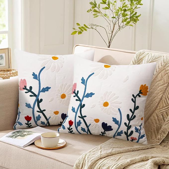 White embroidered throw pillow cover with blue floral branches and small red accents