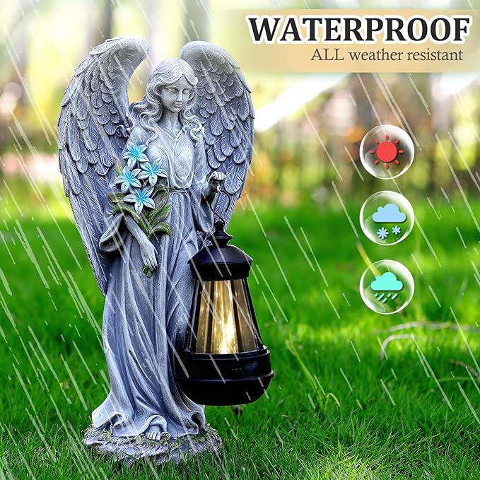 Gray angel garden statue with lantern, standing in grass with raised wings and flower ornament.