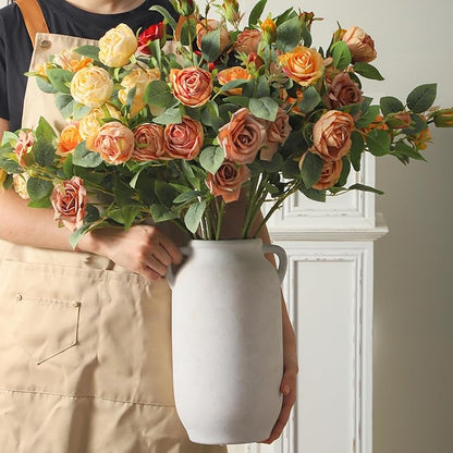 Gray ceramic vase with side handles held by person, filled with rose bouquet