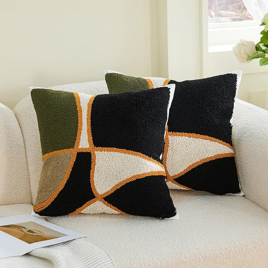 Two square tufted pillow covers: green, black, tan geometric cross with orange edge