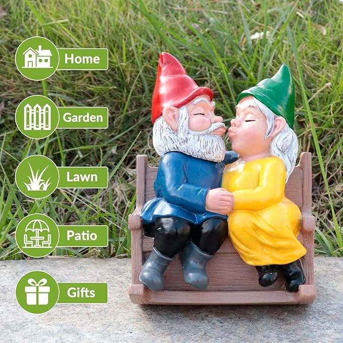 Garden gnome couple rocking chair statue on gravel outdoors, kissing, red and green hats