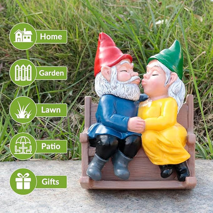 Garden gnome couple rocking chair statue on gravel outdoors, kissing, red and green hats