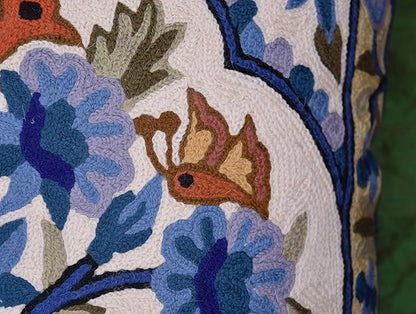Close-up of embroidered bird and blue flowers on a blue floral pillow cover border panel.