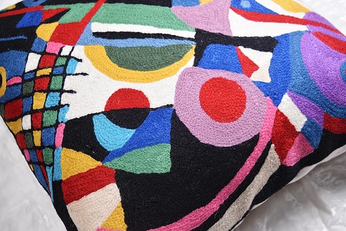 Black abstract embroidered pillow cover close-up with purple, blue, red and yellow shapes.