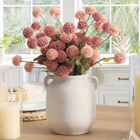 Rustic white ceramic vase with two side handles, holding pink pom-pom flowers.