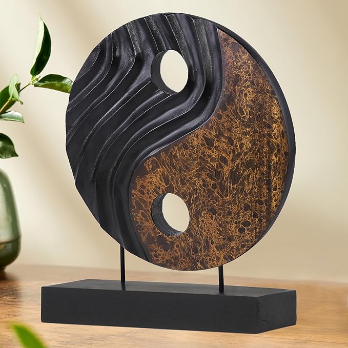 Yin yang wood sculpture with black and brown circular disk, white cutouts, on dark base