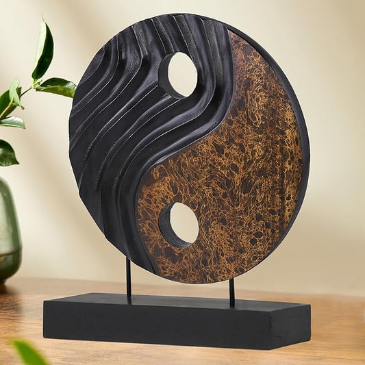 Yin yang wood sculpture with black and brown circular disk, white cutouts, on dark base