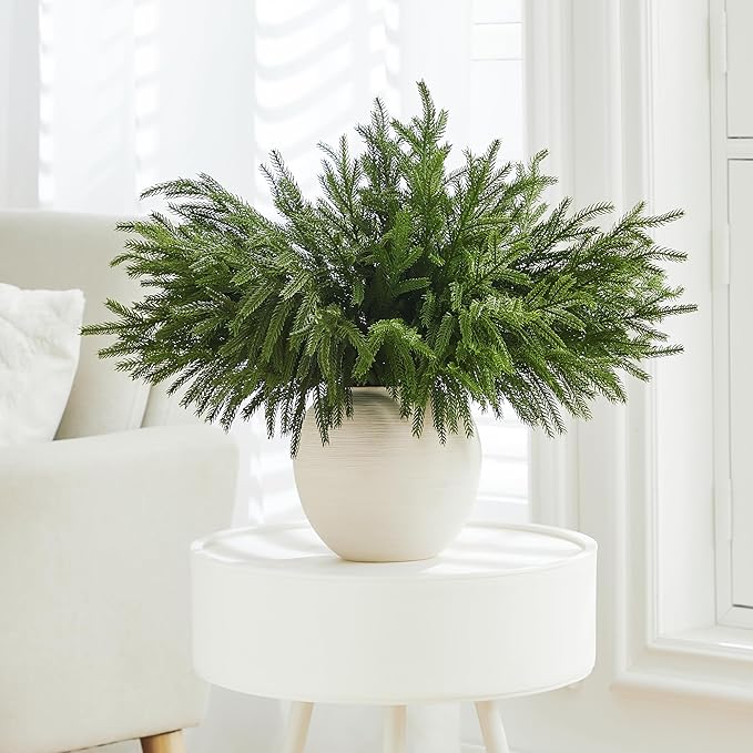 Green faux pine branch stem with dense needles, arranged in a white planter