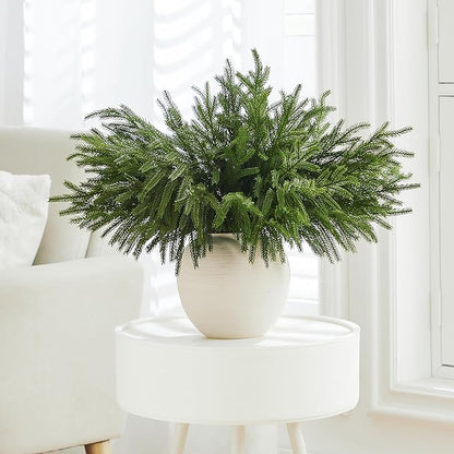 Green faux pine branch stem with dense needles, arranged in a white planter