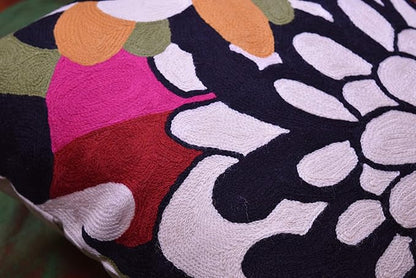 Embroidered floral pillow cover with orange, green, magenta, and black petal pattern