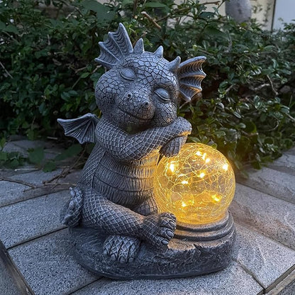 Blue-gray dragon resin figurine holding a glowing glass orb, illuminated outdoor statue