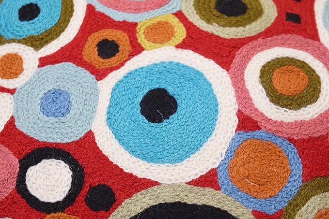 Close-up view of red pillow cover with light blue, orange, and black circle embroidery