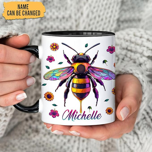 Ceramic coffee mug with bee artwork and 'Michelle' name, black rim, held