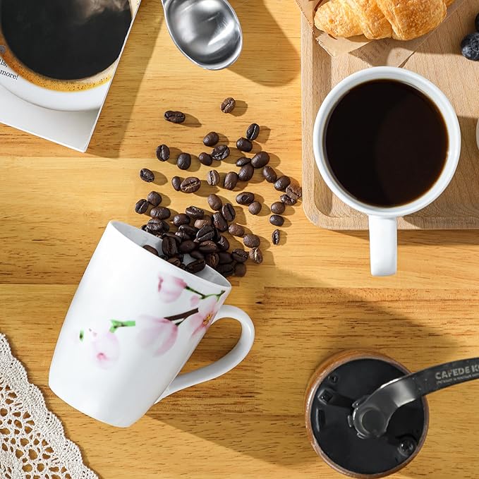 White ceramic coffee mug with pink floral design, filled with dark coffee and handle
