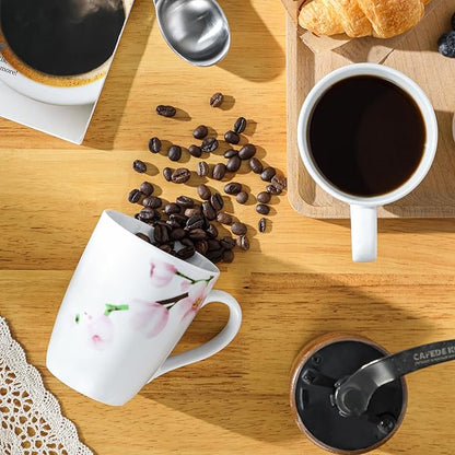 White ceramic coffee mug with pink floral design, filled with dark coffee and handle