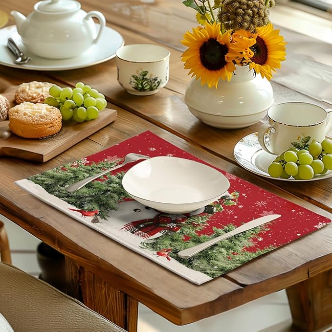 Red snowman placemat on a dining table with plate, cutlery, and pine-tree scene