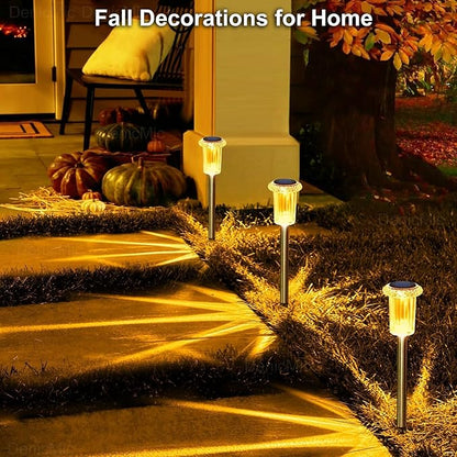Set of amber-glowing solar pathway stake lights near fall yard decorations