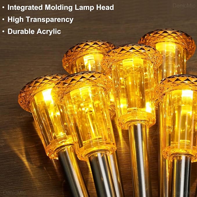Cluster of orange-tinted solar lantern heads with warm amber light on metal stakes