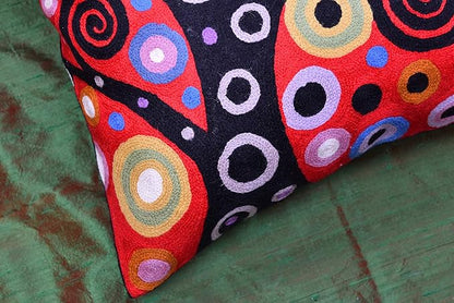 Red and black decorative pillow cover corner with spiral circles and dot accents.
