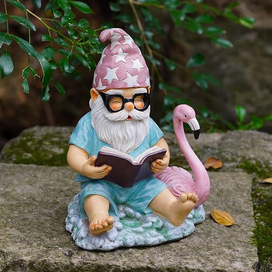 Garden gnome resin statue reading book with pink flamingo figurine, sitting on stone