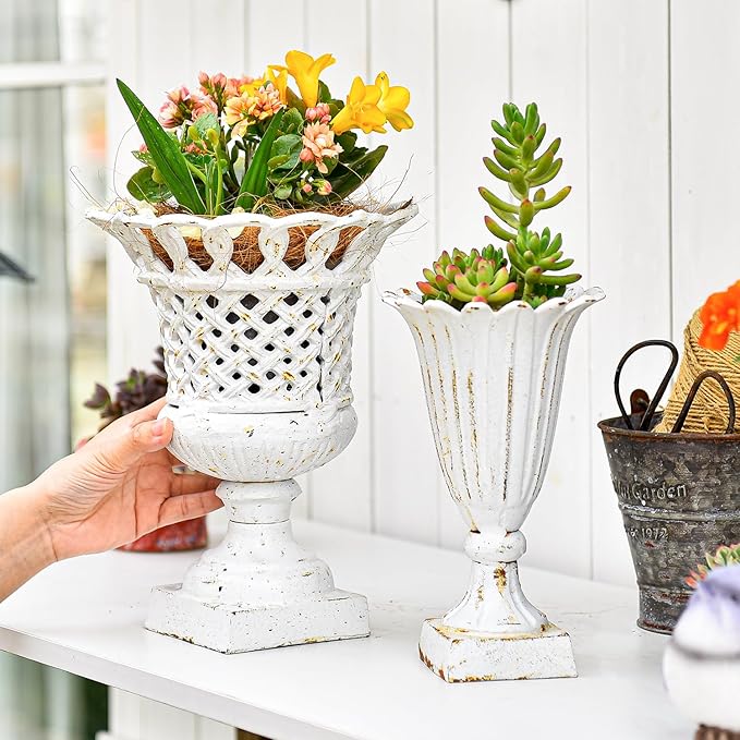 Antique white openwork urn planter with pedestal base, held in hand with flowers inside