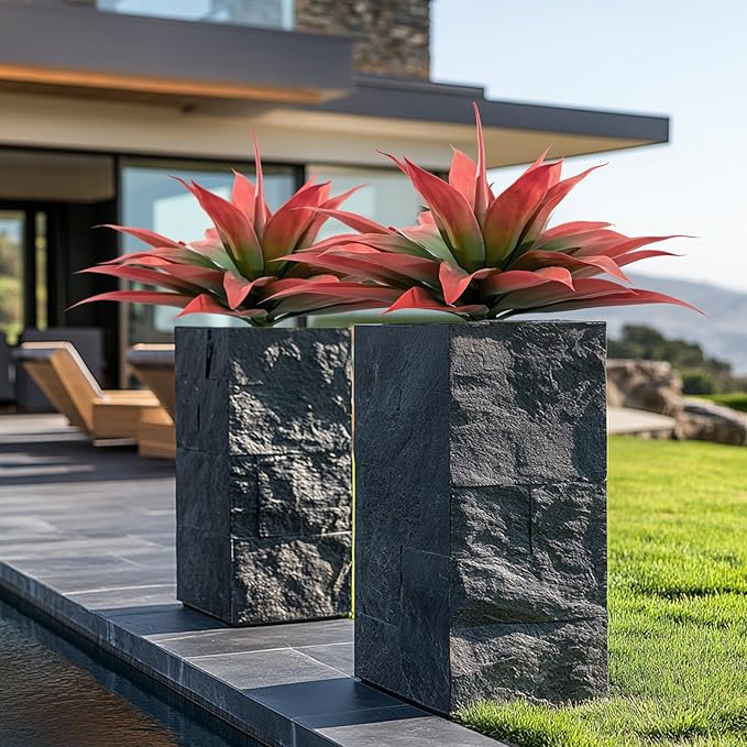 Pair of red and green faux agave plants in dark stone planters outdoors