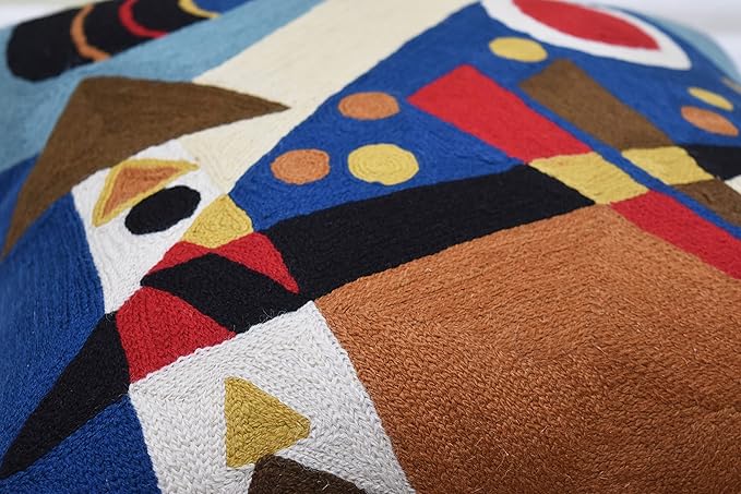 Close-up of blue abstract pillow cover with red stripe, cream shapes, and brown fabric