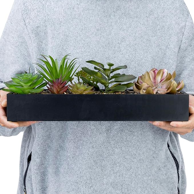 Hands holding a black rectangular faux succulent planter with multiple plant varieties