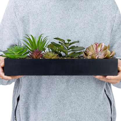 Hands holding a black rectangular faux succulent planter with multiple plant varieties