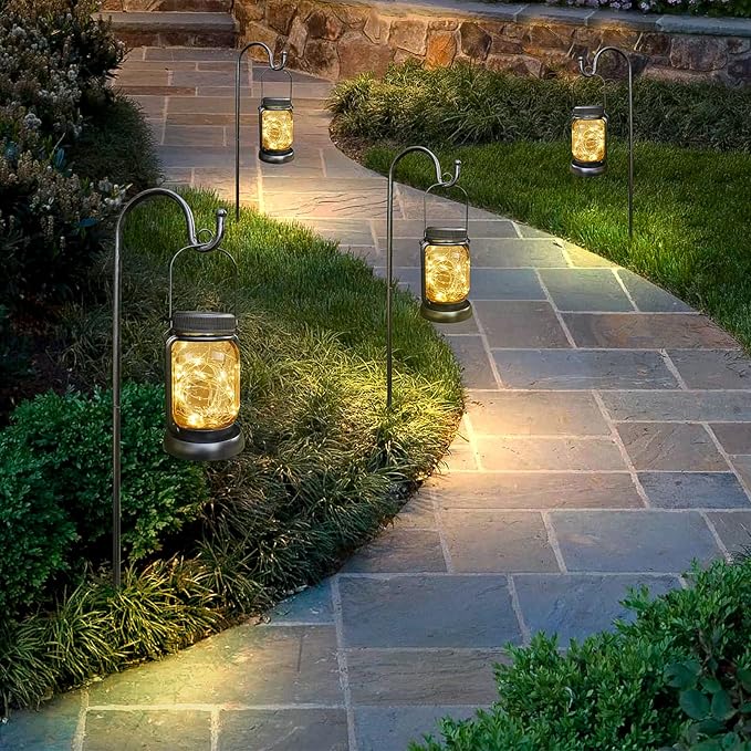 Multiple solar hanging jar lanterns with warm light lined along a yard walkway