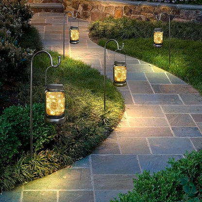 Multiple solar hanging jar lanterns with warm light lined along a yard walkway