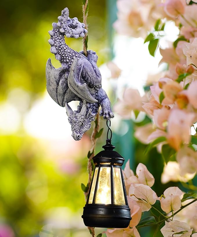 Stone-gray dragon figurine with hanging black lantern among pink blossoms