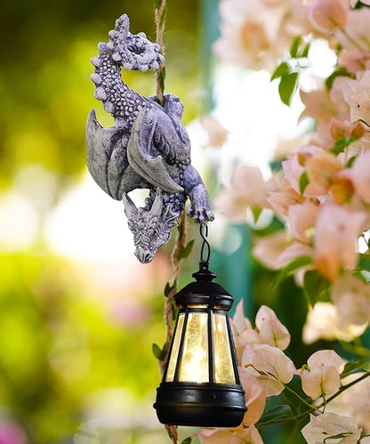 Stone-gray dragon figurine with hanging black lantern among pink blossoms