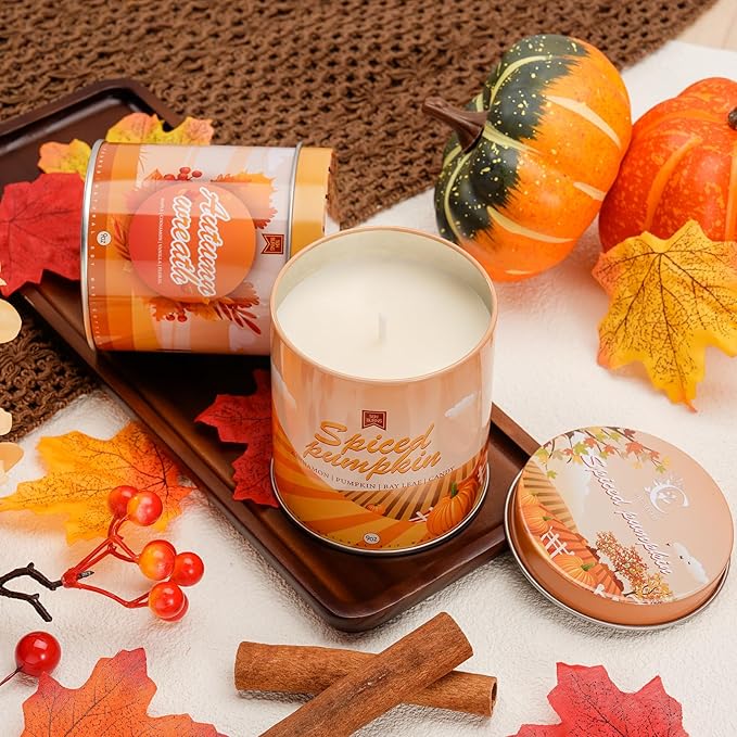 Autumn scented soy candle jar with lid, cinnamon sticks, and pumpkins with orange leaves