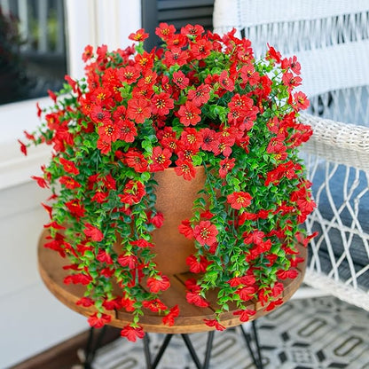 Red faux hanging flower bundle with green vines over wooden planter, cascading blooms