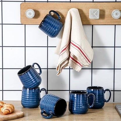 Blue ceramic espresso mugs with handles and black interiors on a tiled counter