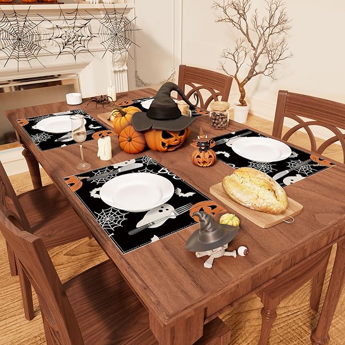 Halloween placemat set of 4 on a dining table; black mats with pumpkins, ghosts, bats.
