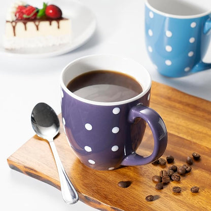Purple ceramic coffee mug with white polka dots and handle, on wooden board with coffee.