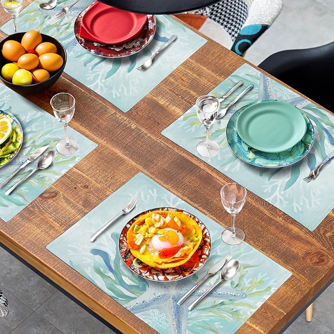 Set of teal blue ocean placemats with starfish and seaweed print spread across a table