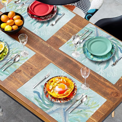 Set of teal blue ocean placemats with starfish and seaweed print spread across a table