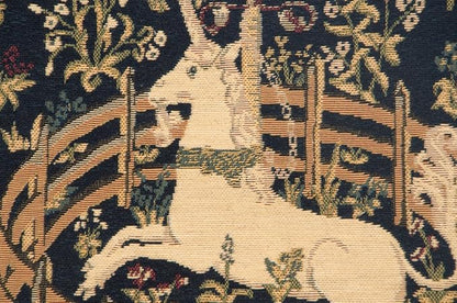 Close-up woven pillow cover: tan unicorn figure in navy floral tapestry