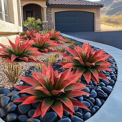 Red and green faux agave plants in blue planters along a rock garden bed