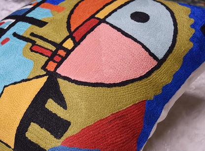 Blue abstract pillow cover detail with face motif, yellow blocks and red accents