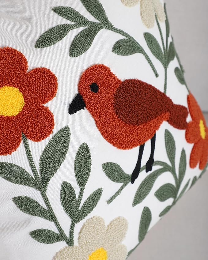 Close-up bird embroidery on pillow cover with green leaves and orange flowers