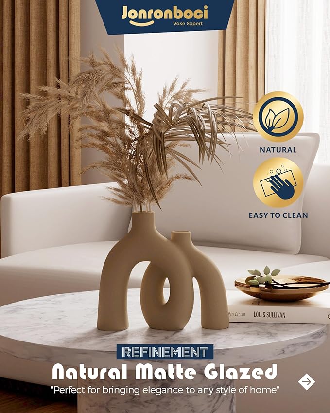 Matte tan-brown ceramic hug vase with arched donut cutout openings, on stand.