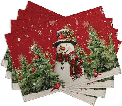 Four red Christmas placemats stacked, featuring a snowman, pine trees, and cardinals