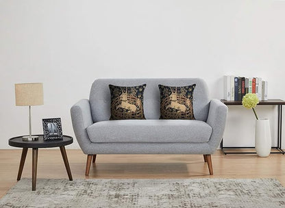 Set of two navy tapestry pillow covers with tan unicorn scenes on a sofa
