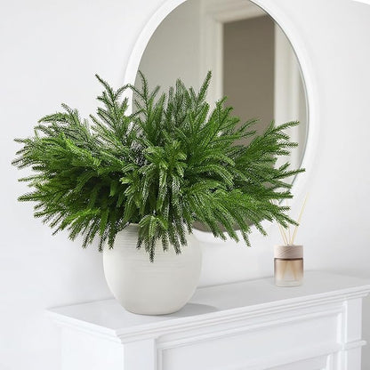 Green faux pine branch stem with full needle clusters in a white vase