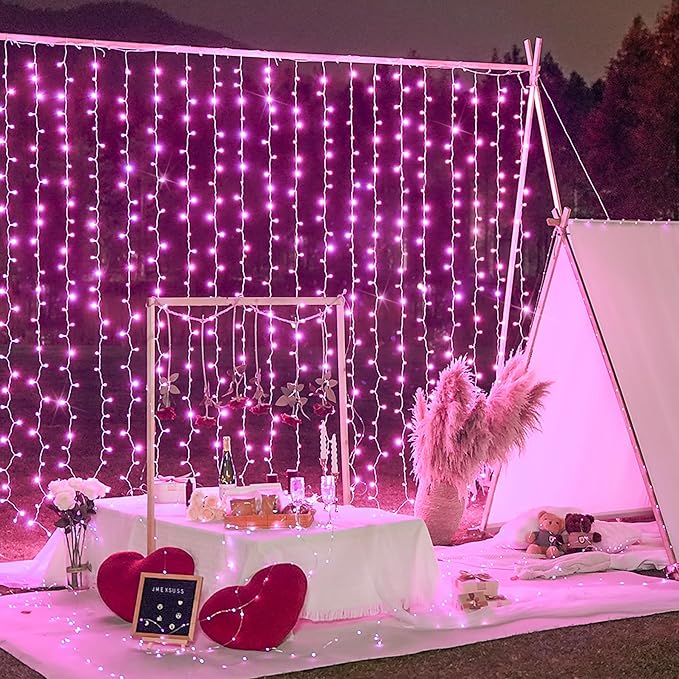 Pink LED curtain string lights draped over a window backdrop with controller