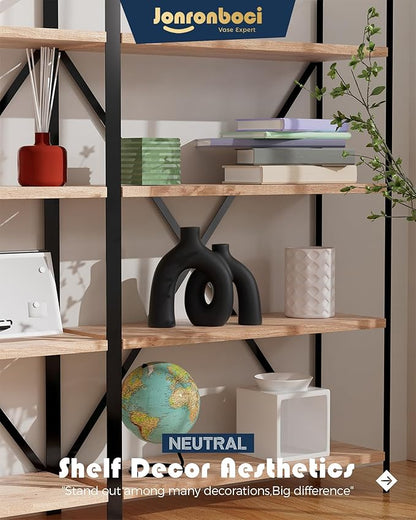 Matte black ceramic hug vase on a shelf, two joined donut-like shapes with openings